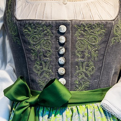 Närbild av en traditionell klänning med broderad korsett och grön rosett.